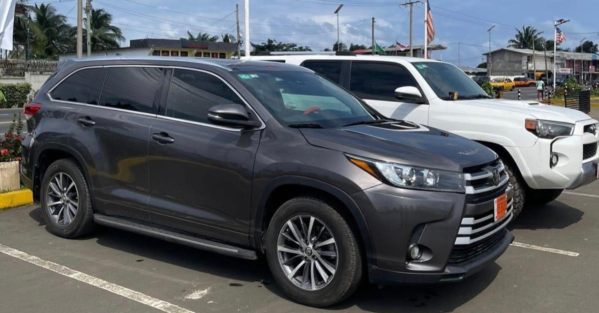 A grey Toyota Highlander and a white Toyota 4Runner from the ITS fleet parked in daylight in Monrovia